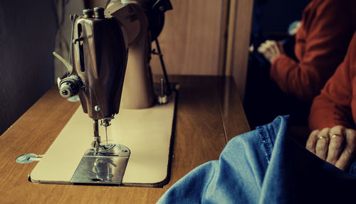 Midsection of woman sewing denim on machine