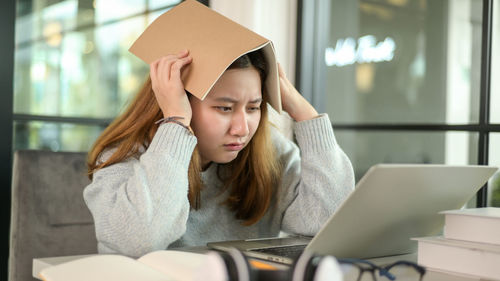 Young woman using mobile phone while sitting on table
