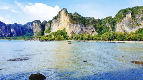 Scenic view of sea by mountain against sky