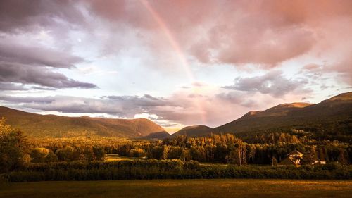 Scenic view of rainbow over mountains during sunset