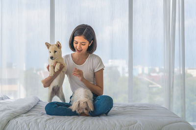 Woman with dog sitting on bed