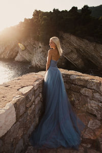 Bride standing by retaining wall against sea