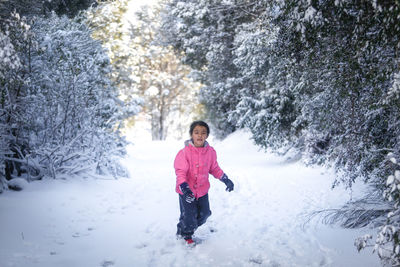 Full length of girl standing on snow covered trees during winter