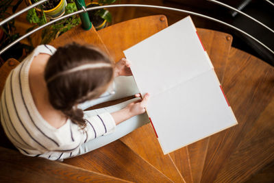 Top view shot of a happy young beautiful woman sitting on the stairs reading a book enjoying