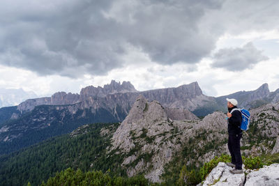 Side view of man looking at mountains against cloudy sky