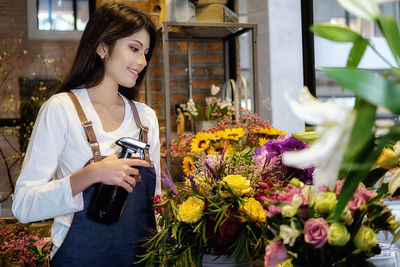 Florist spraying water on flowers at shop