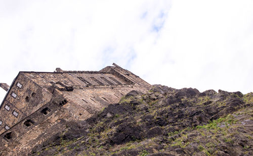 Low angle view of castle on mountain against sky