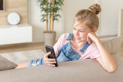Girl using smart phone on sofa at home