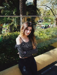 Portrait of smiling young woman standing against trees