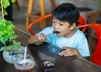 High angle view of boy eating dessert while sitting in restaurant