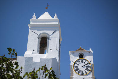 Low angle view of clock and bell tower of church against clear blue sky