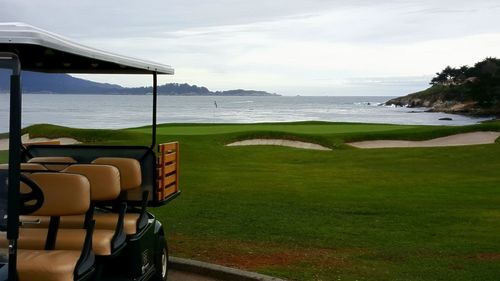 Scenic view golf course by sea against sky