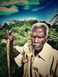 Portrait of man standing by tree against sky