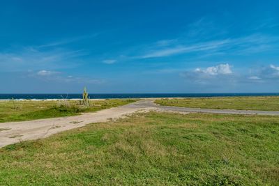 Scenic view of field and sea against blue sky