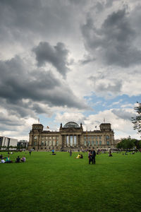 People in lawn against cloudy sky