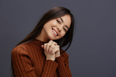 Woman with hands intertwined against gray background