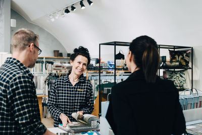 Smiling saleswoman showing wallpaper sample to customer in store