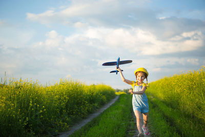 Woman holding umbrella on field against sky