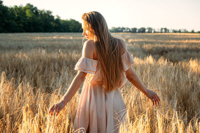 Get into wild, connect to nature. happy woman enjoying life and nature on sunset wheat field