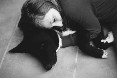 High angle view of girl embracing dog lying on floor