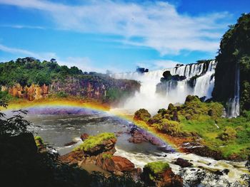 Scenic view of waterfall against rainbow in sky