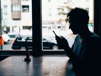 Side view of man using mobile phone in bus