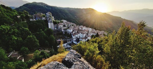 High angle view of buildings and mountains against sunset sky