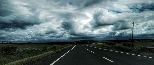 Empty road against cloudy sky