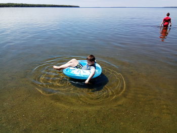 Boy on inflatable ring floating in lake