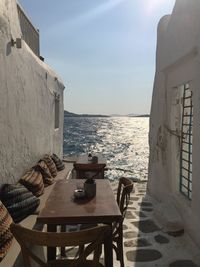 Chairs and table on beach by sea against sky