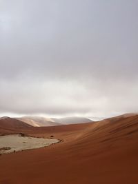 View of desert against cloudy sky