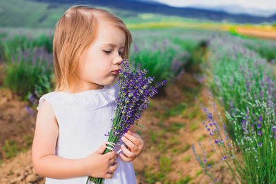 Cute girl holding flower standing on field