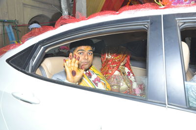 Portrait of man waving seen through car window