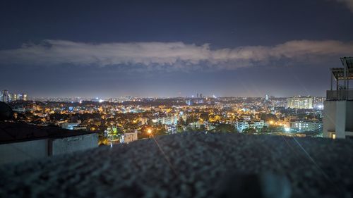 High angle view of illuminated city buildings against sky at night