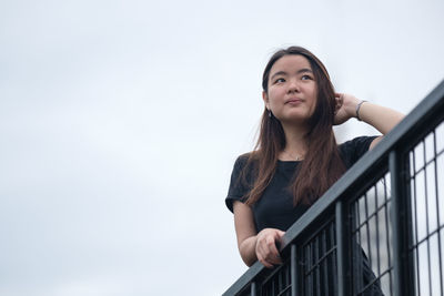 Low angle view of young woman standing against clear sky