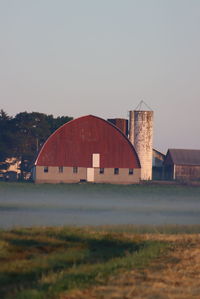 Built structure on field by lake against clear sky