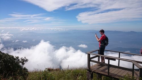 Man photographing while standing at observation point against sky