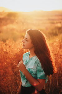 Side view of a young woman standing on field