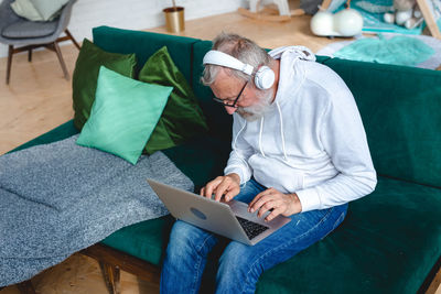 Man using mobile phone while sitting on sofa at home