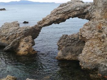 Rock formation on beach against sky