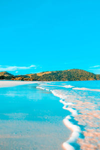 Surface level of swimming shore at beach against blue sky