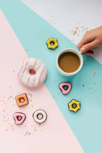 Directly above shot of hands holding coffee by donut on table