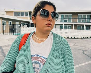 Portrait of young woman wearing sunglasses standing in city