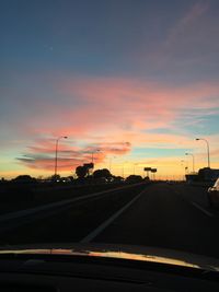 Road seen through car windshield during sunset