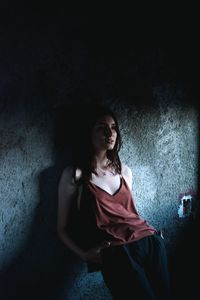 Portrait of woman sitting against wall at home