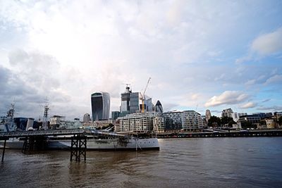 Buildings by river against sky in city