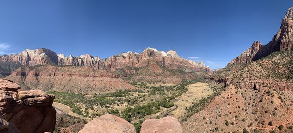 Panoramic view of rocky mountains against clear blue sky