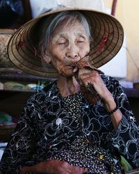Senior woman with eyes closed wearing asian style conical hat