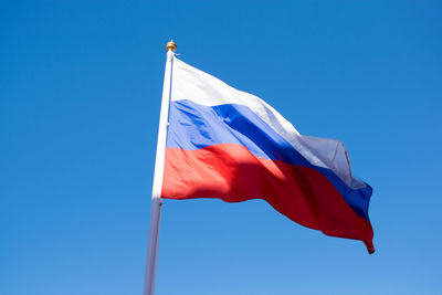 Low angle view of flag against clear blue sky