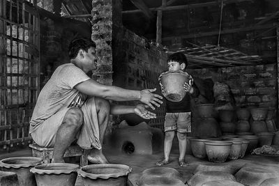 Father looking at son holding pottery in workshop